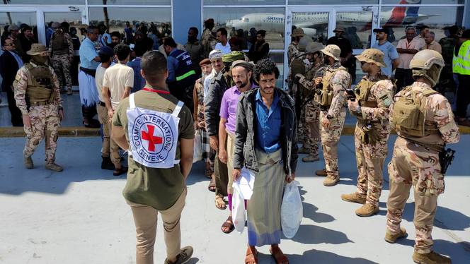 Freed Houthi prisoners stand as they wait to board an International Committee of the Red Cross (ICRC)-chartered plane at Aden Airport, in Aden.