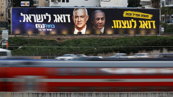 Traffic moves past a Blue and White party election campaign poster, depicting party leader Benny Gantz, and Israeli Prime Minister Benjamin Netanyahu, in Tel Aviv, Israel, February 18, 2020.