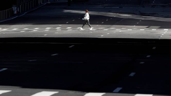 A woman walks across an empty 10th Avenue in Manhattan during the outbreak of the coronavirus disease in New York City, New York, US, March 26, 2020