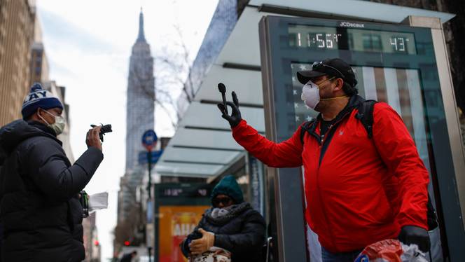 Felix Guzman, right, waves wears protective gloves and masks due to Covid-19 concerns as he waves goodbye after handing out disposable gloves and sanitizing wipes to people who are homeless on 34th Street, Saturday, March 21, 2020, in New York.