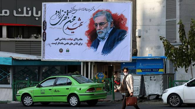 An Iranian man walks by a billboard of slain Iranian nuclear scientist Mohsen Fakhrizadeh in Tehran, on November 30, 2020.