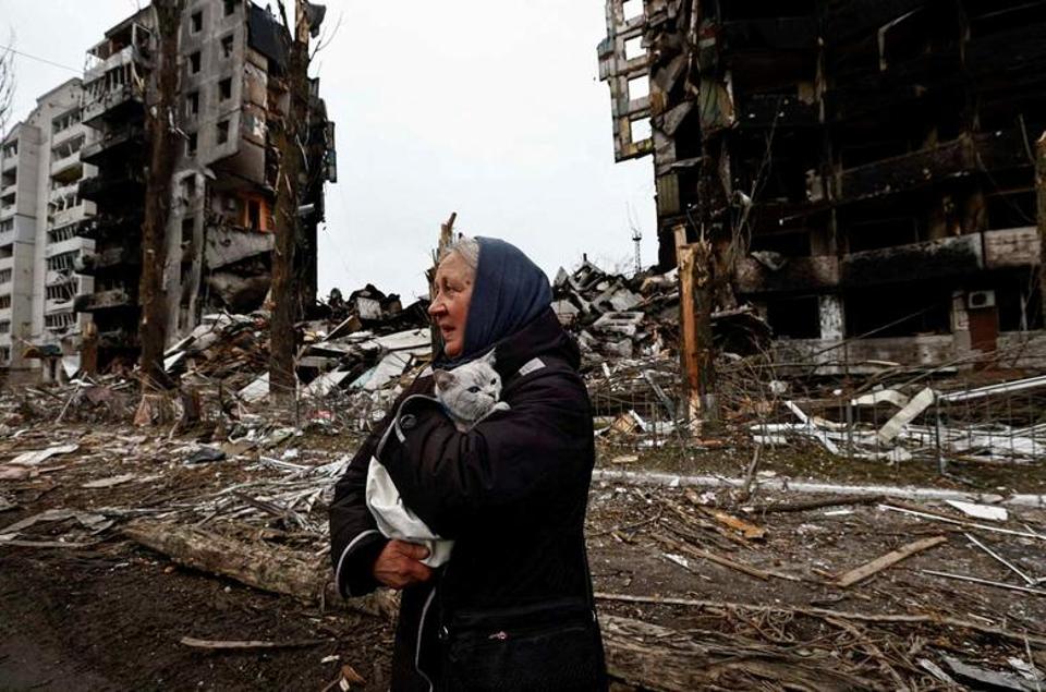 A woman carries her cat as she walks past buildings that were destroyed by Russian shelling, amid Russia's attack in Borodyanka, in the Kiev region, Ukraine, April 5, 2022.