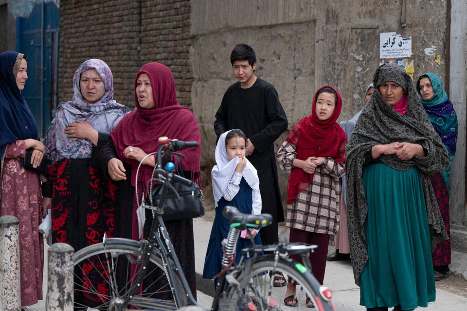Relatives of victims wait to search for their loved ones outside a hospital in Kabul