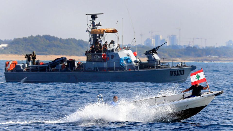Lebanese protesters on a motorboat carry their national flag as they sail in front on an Israeli Navy vessel during a demonstration demanding Lebanon's right to its maritime oil and gas fields, in the southern marine border town of Naqoura, Lebanon, Sunday, Sept 4, 2022.