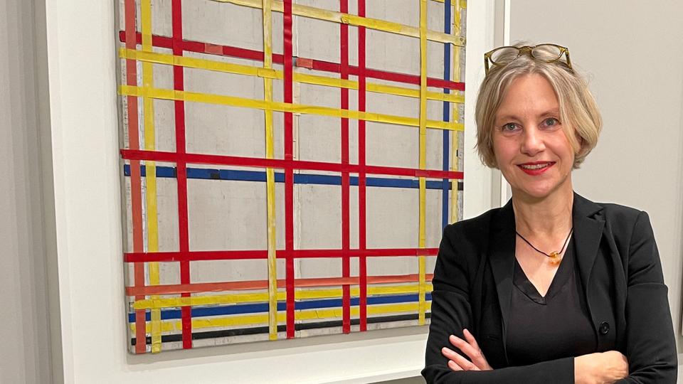 Curator Susanne Meyer-Bueser poses in front of the Piet Mondrian painting