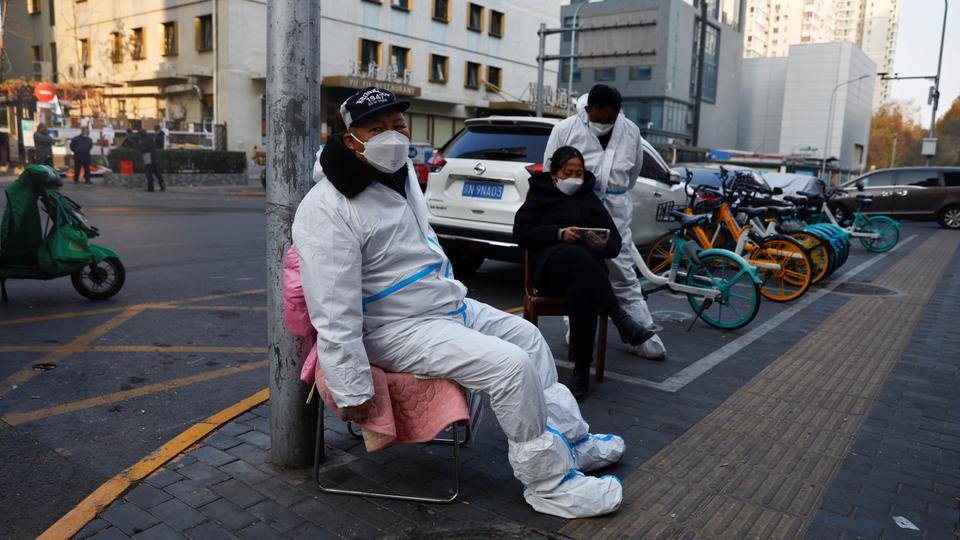A worker in a protective suit sits near a residential compound, following the coronavirus disease outbreak in Beijing on November 23, 2022.