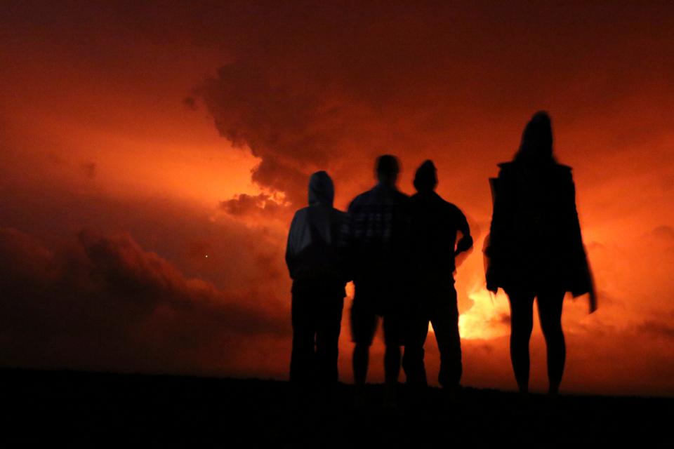 People watch the glow from lava erupting.