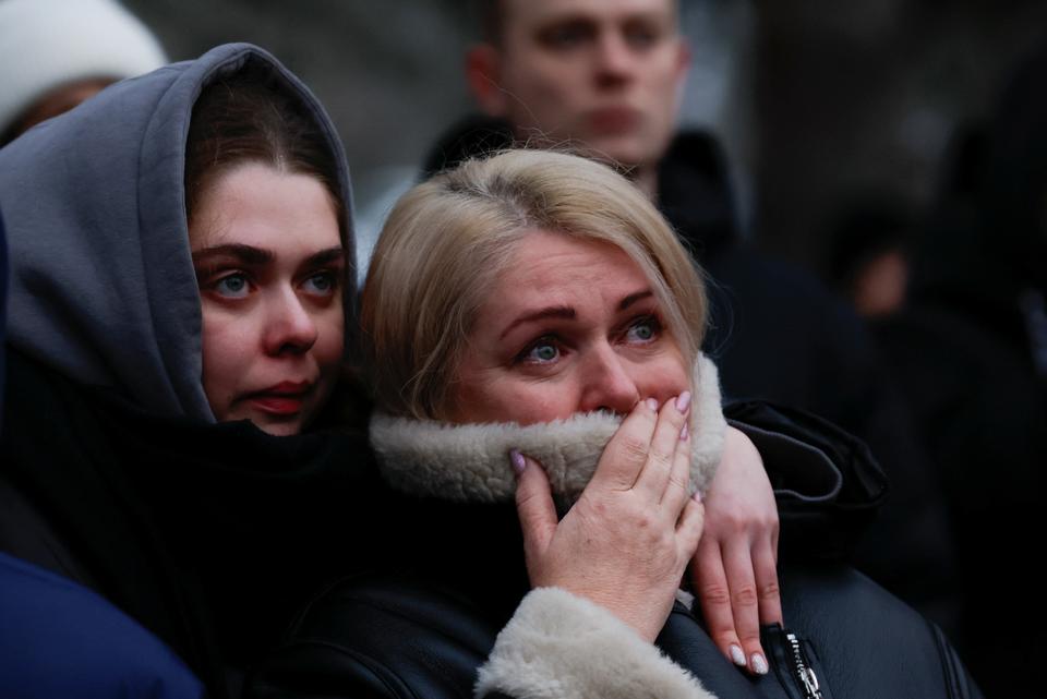 Women look on as emergency personnel work at the site of the strike in Dnipro, the worst the city has witnessed since the war began.