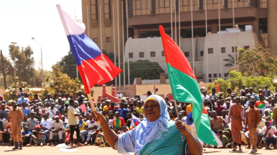 A woman holds her national flag and Russian flag as people demand departure of French ambassador and troops in capital Ouagadougou.