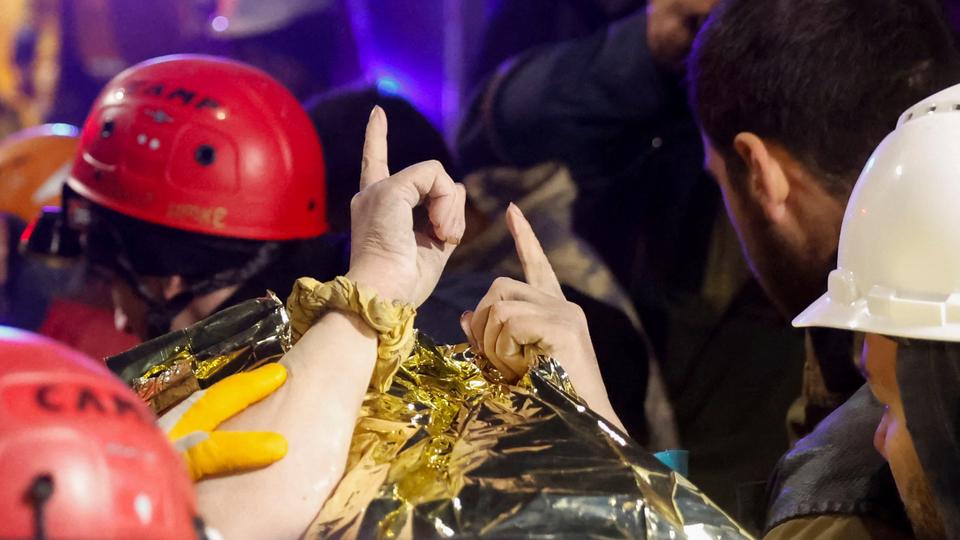 Fatma, a 15-year-old, points her fingers to the sky after being rescued from the rubble of a collapsed building hours after the quake, in the aftermath of a deadly earthquake in Hatay, Turkey February 14, 2023.