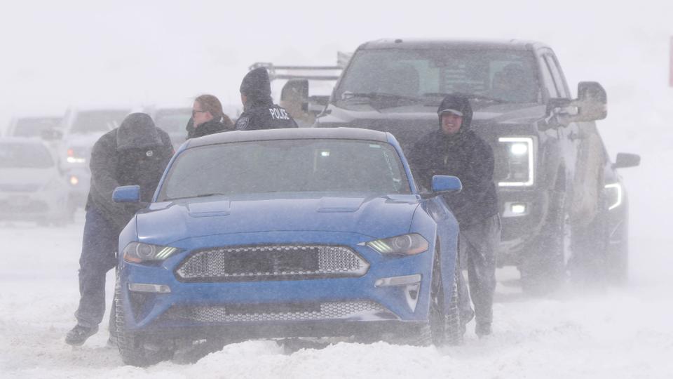 People push a car out of the snow on Mountain View Parkway in Lehi, Utah, on February 22, 2023.
