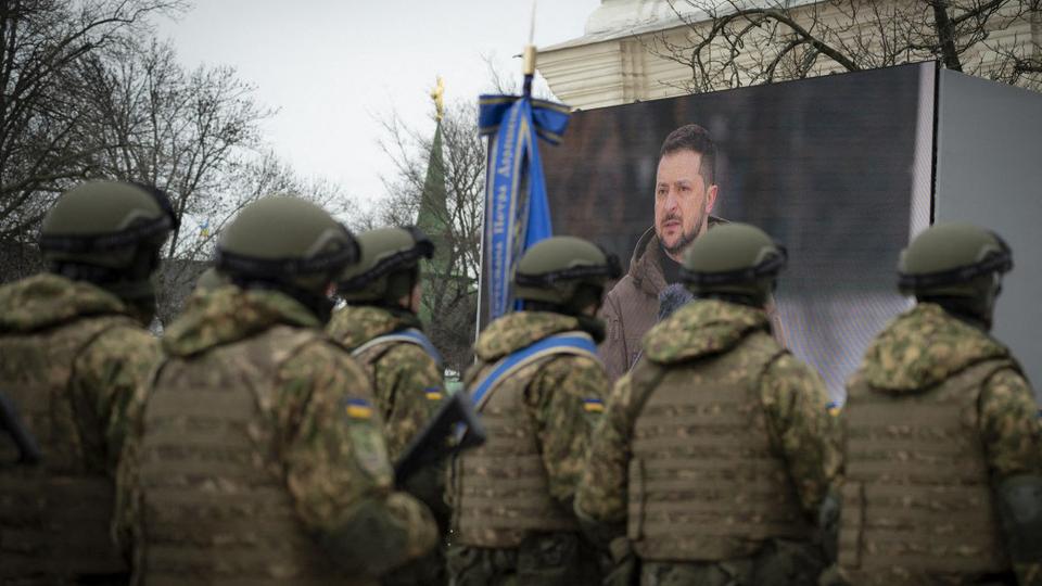 Ukrainian soldiers attend a ceremony with Ukrainian President Zelenskyy shown on a screen at St Sophia Square in Kiev.