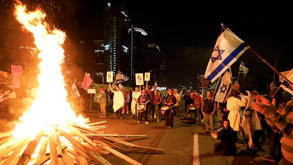 People stand next to a bonfire on a road during a protest against Israeli far-right coalition in Tel Aviv on February 25, 2023.