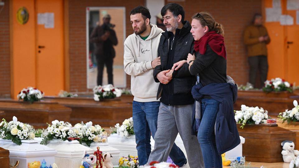 Mourners walk by coffins as they bid farewell to the victims.