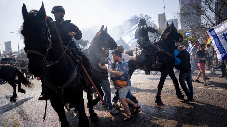 Israeli police deploy horses and stun grenades to disperse Israelis blocking a main road during the protests.