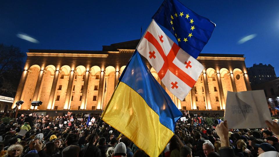 A protester waves the Georgian, Ukrainian and European flags during a demonstration outside the parliament in Tbilisi.