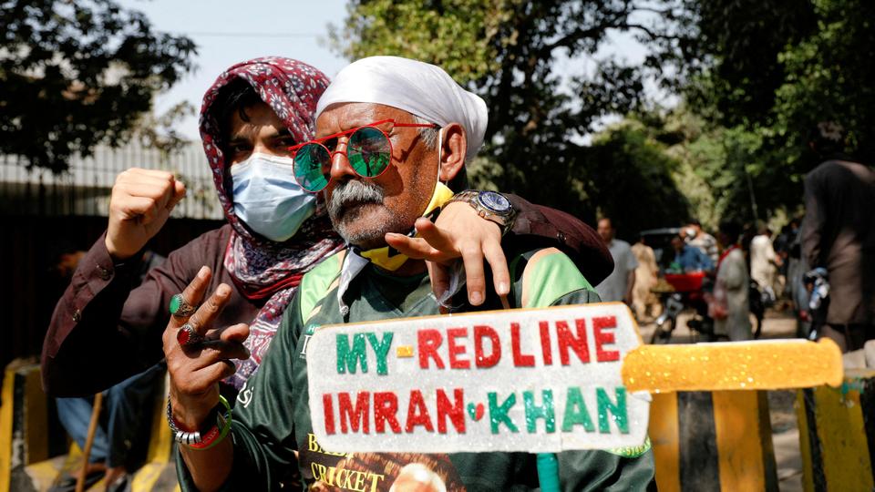 Supporters of former Pakistan Prime Minister Imran Khan, pose with a placard in a shape of a cricket bat, with
