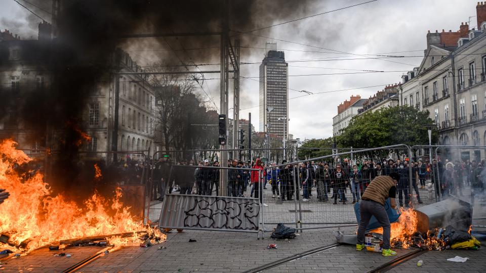 A protestor feeds a burning barricade during a demonstration in Nantes, western France.