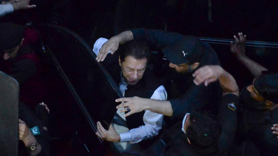 Security personnel make way for former Prime Minister Imran Khan, centre, as he arrives to appear in a court, in Lahore, Pakistan on Friday March 17, 2023.