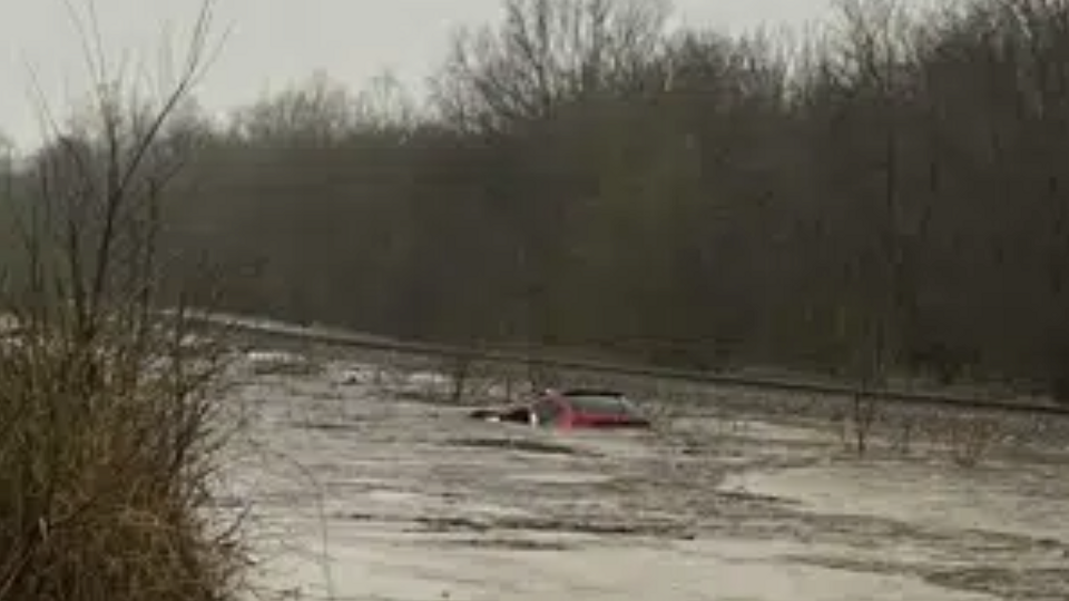 In this photo provided by Layton Hoyer, a red SUV is seen submerged in floodwater on Old Ritchey Road in Granby, Missouri. Hoyer rescued an elderly woman from the car.