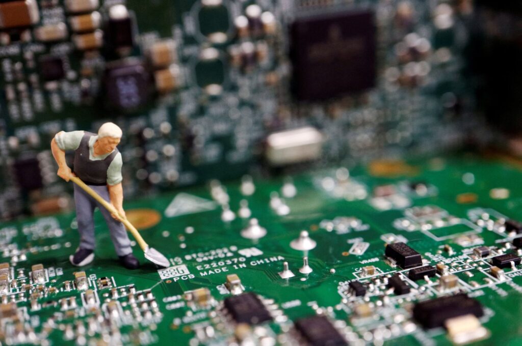 A worker miniature is placed among printed circuit boards with semiconductor chips, in this illustration picture taken July 5, 2023. (Reuters Photo)