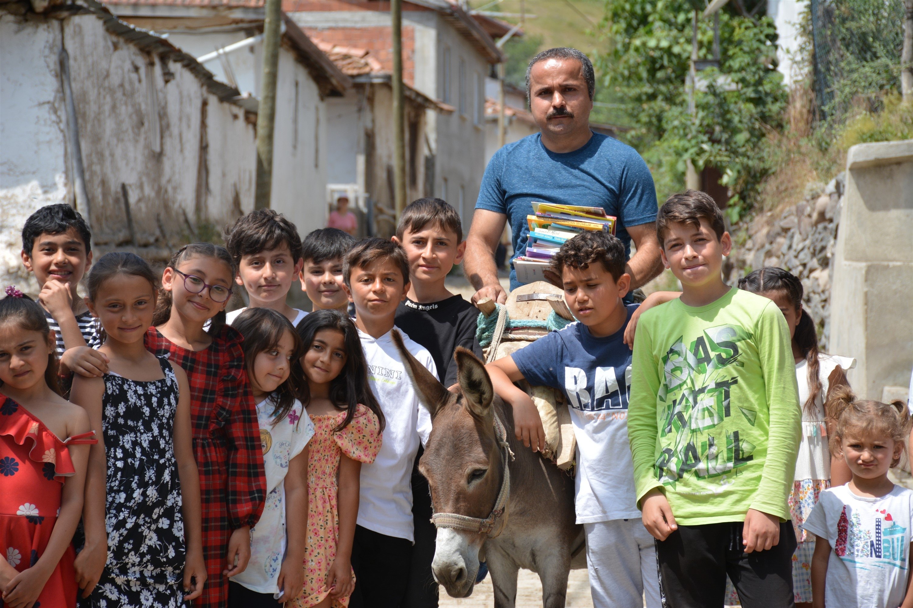 281952 Metin Uğur poses with books on his donkey and children in Karacaören, Tokat, Türkiye, July 11, 2023. (DHA Photo)