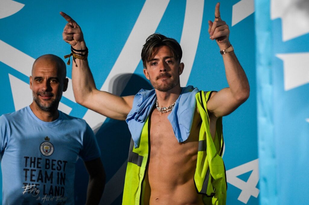Manchester City's English midfielder Jack Grealish (R) celebrates next to Manchester City's Spanish manager Pep Guardiola (L) on stage following an open-top bus victory parade for their European Cup, FA Cup and Premier League victories, Manchester, U.K., June 12, 2023. (AFP Photo)