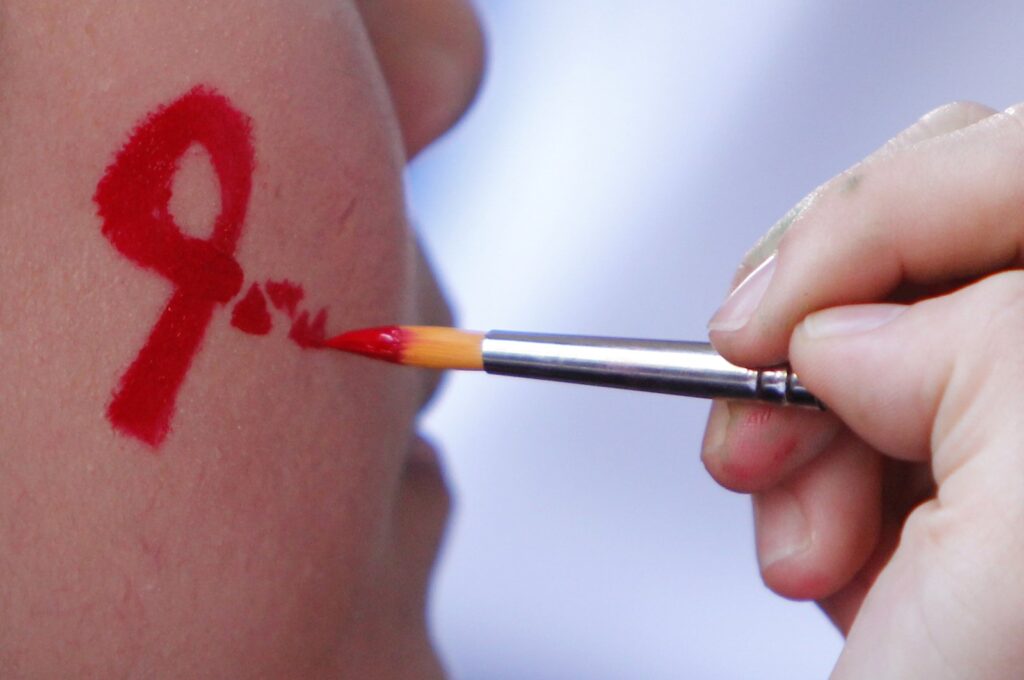 A woman gets her face painted with a red ribbon during a World AIDS Day awareness campaign, Kuala Lumpur, Malaysia, Dec. 1, 2012. (AP Photo)