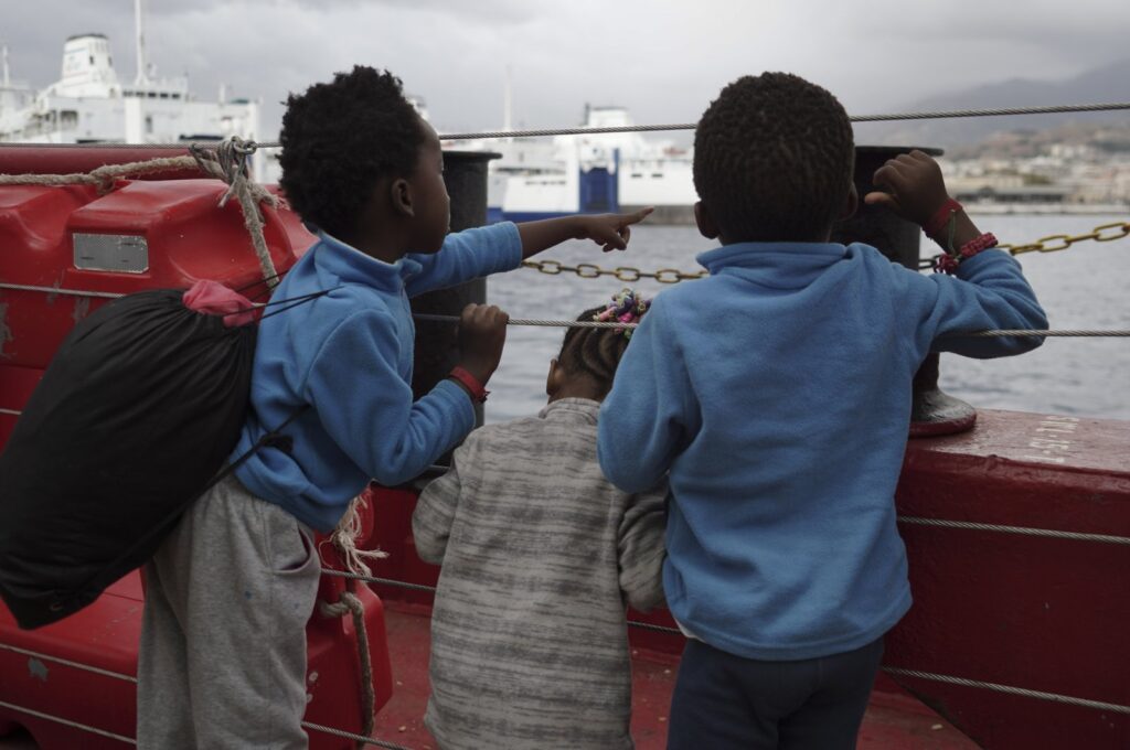 Children wave at a boat from aboard the Ocean Viking as it reaches the port of Messina, Italy, Sept. 24, 2019. (AP Photo)