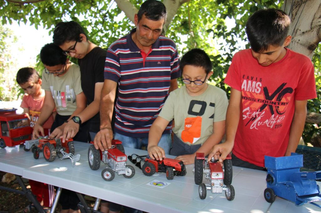 Mustafa Ercan (C) is photographed along with happy kids playing with tractors made by repurposing waste materials, Mersin, southern Türkiye, July 17, 2023. (AA Photo)