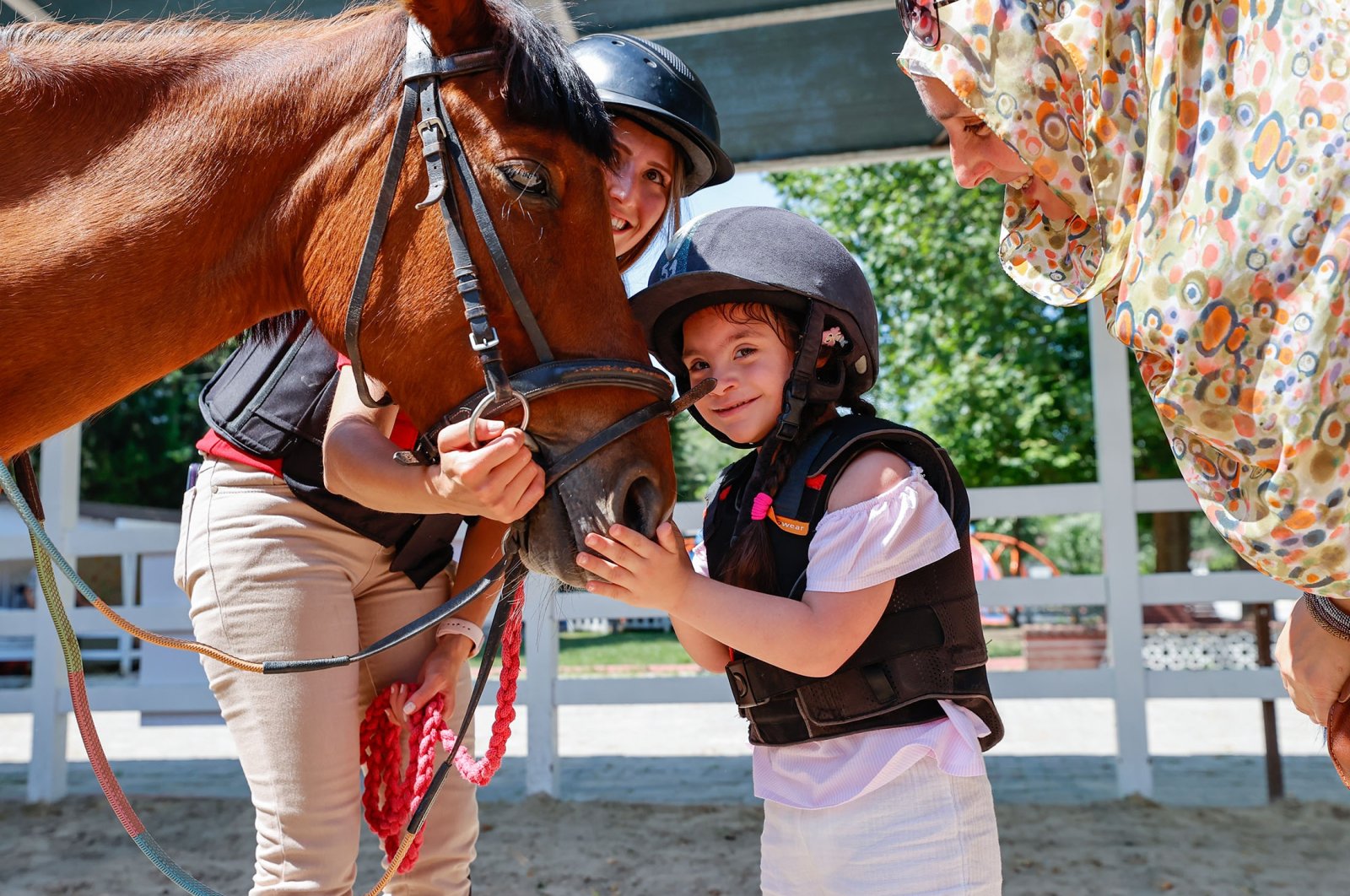A disabled child pets a horse at Türkiye Jockey Club Equine Therapy Center, in Izmir, Türkiye, July 15, 2023. (AA Photo)