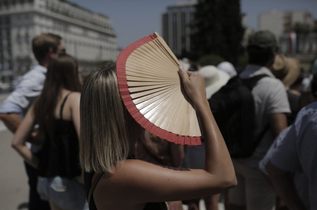A tourist uses her hand-held fan to cover her face as she watches Greek Presidential guards performing their duties in front of the parliament building during an extreme heat wave, Athens, Greece, 14 July 2023. (EPA Photo)
