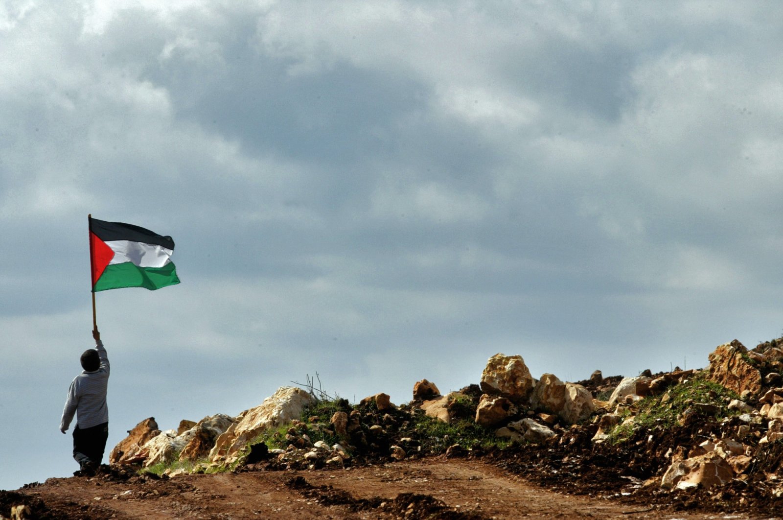 A boy holds a Palestinian flag during a march against the construction of a section of Israel's separation barrier in the outskirts of the village of Iskaka, near the Jewish West Bank settlement of Ariel, Palestine, Jan. 25, 2005. (AP File Photo)