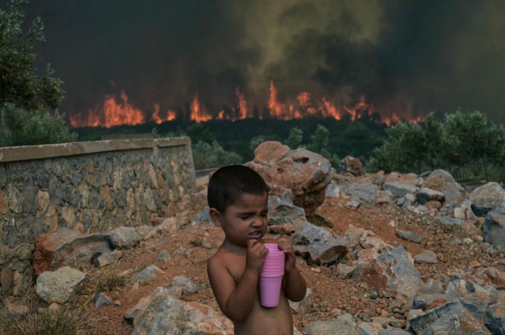 A child reacts as a wildfire burns in the village of Agios Charalabos, near Athens, July 18, 2023. (AFP Photo)