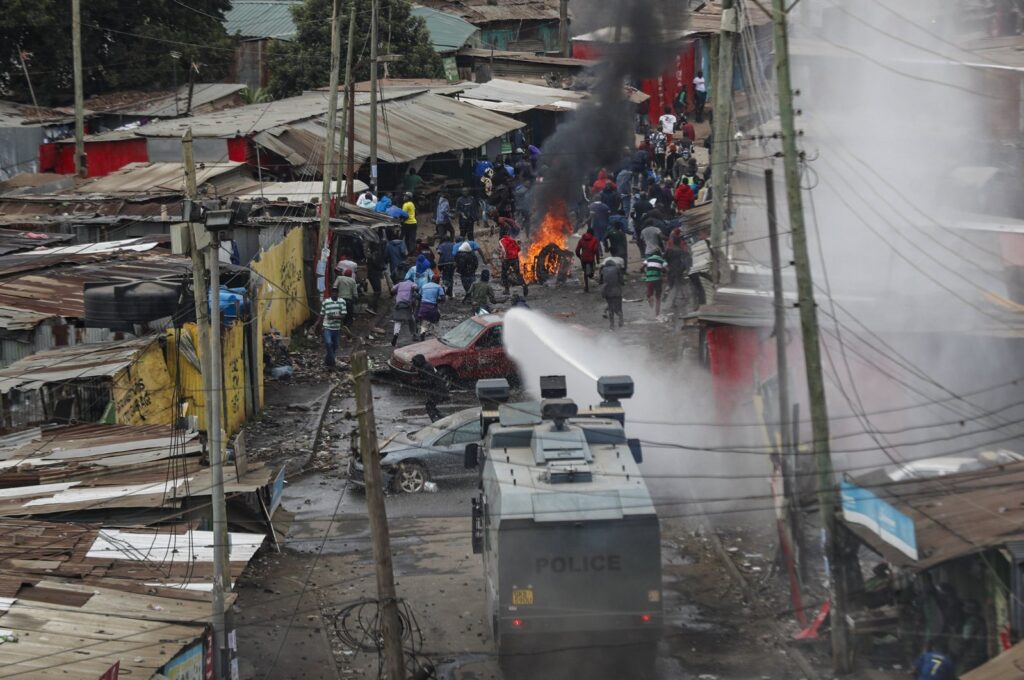 Protesters throw rocks at police during clashes next to a cloud of teargas in the Kibera area of Nairobi, Kenya, July 19, 2023. (AP Photo)