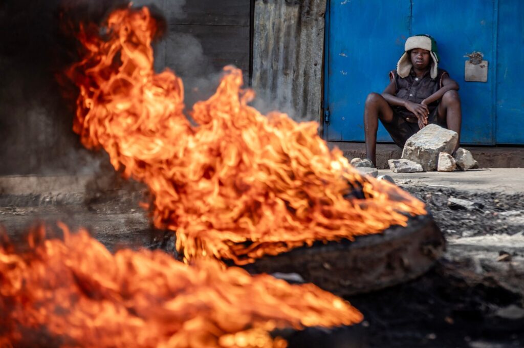 A young Kenyan sits next to a burning barricade used to block a main road during the third day of anti-government protests, Nairobi, Kenya, July 21, 2023. (AFP Photo)