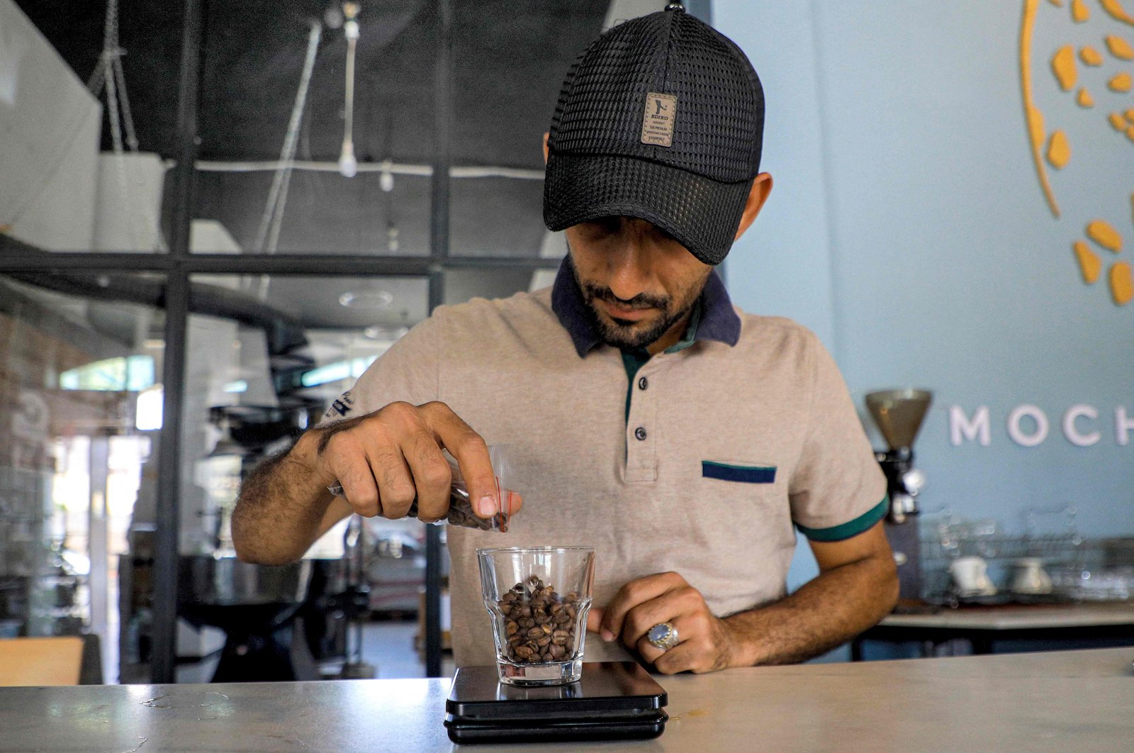 A specialty coffee shop employee weighs a cupful of roast coffee grains before grinding them at the shop in Sanaa, Yemen's Houthi-held capital, July 23, 2023. (AFP Photo)