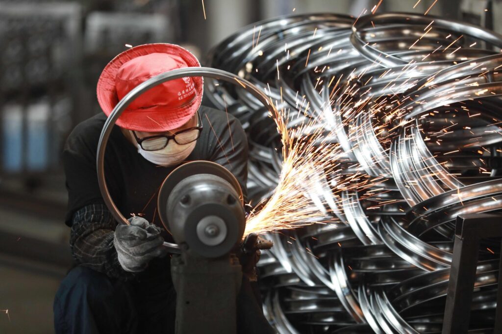 A worker polishes a bicycle wheel at a factory producing bicycle parts for export in Hangzhou, in China's eastern Zhejiang province, July 11, 2023. (AFP Photo)