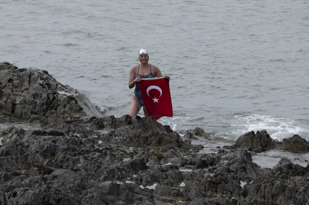 Turkish swimmer Aysu Türkoğlu unfurls a Turkish flag upon reaching Scotland, Aug. 9, 2023. (AA Photo)