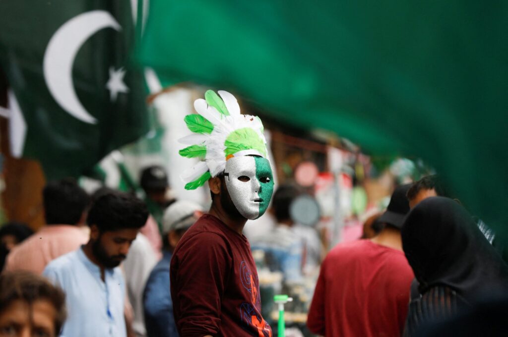 A vendor wears a mask and a headwear with the colours of the Pakistani flag, while selling national flags and patriotic memorabilia, ahead of Pakistan's Independence Day, along a market in Karachi, Pakistan, Aug. 2, 2023. (Reuters Photo)