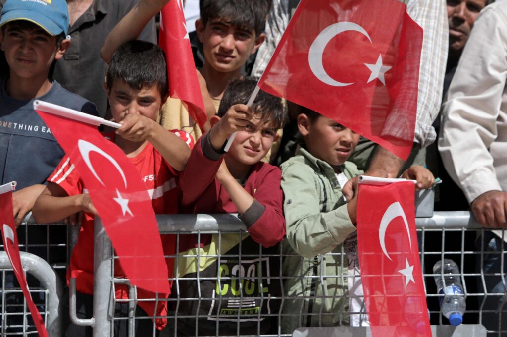 Syrian children wave Turkish flags as they attend the inauguration of a Qatari-funded Turkish housing complex project for the internally displaced, Ghandoura area, Jarablus, Syria, May 24, 2023. (AFP Photo)