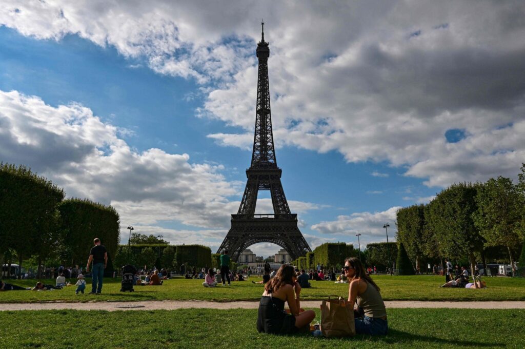 Tourists and Parisians sit in the Champ de Mars in front of the Eiffel Tower, Paris, France, Aug. 9, 2023. (AFP Photo)
