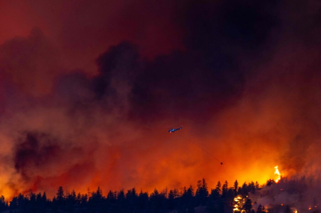 A helicopter battles the McDougall Creek wildfire as it burns in the hills West Kelowna, British Columbia, Canada, Aug.17, 2023. (AFP Photo)