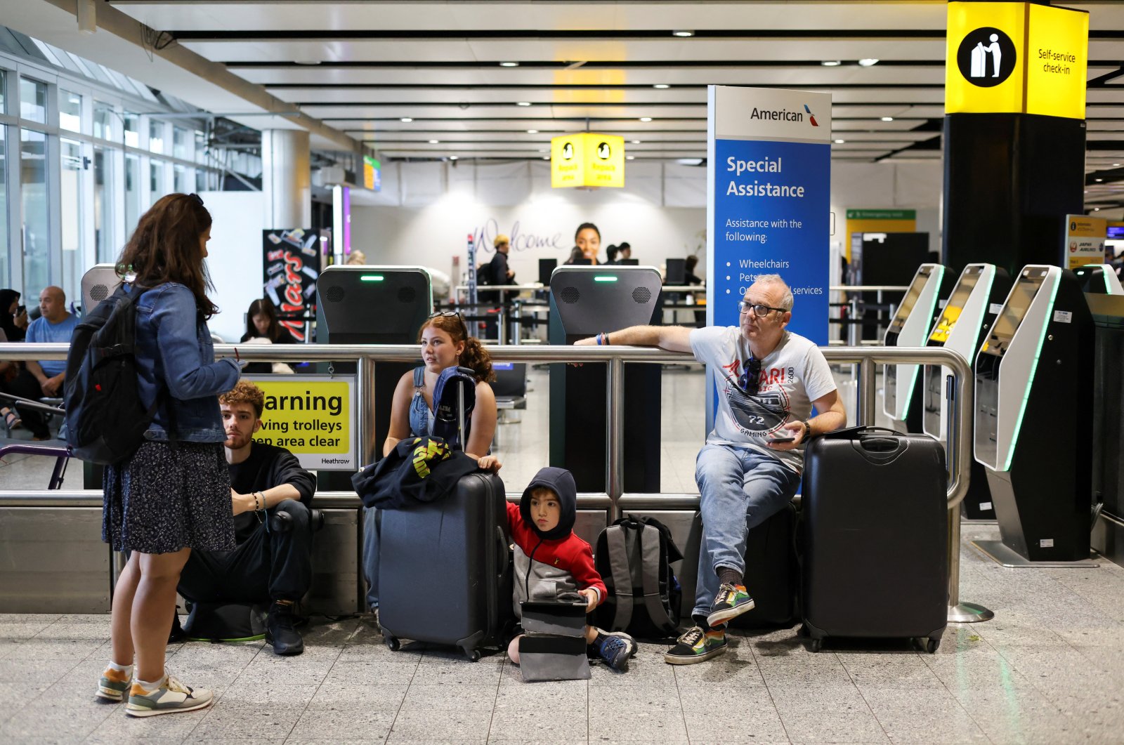 A family waits as their flight delays as Britain's National Air Traffic Service (NATS) restricts U.K. air traffic due to a technical issue causing delays, in London, United Kingdom, Aug. 28, 2023. (Reuters Photo)
