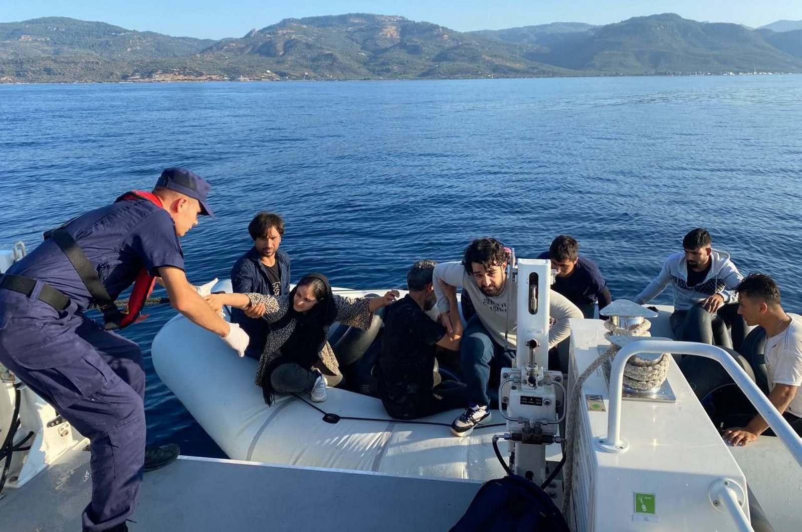 A Turkish officer helps 18 irregular migrants pushed back by Greece off the coast of western Çanakkale province, Türkiye, Aug. 30, 2023. (AA Photo)