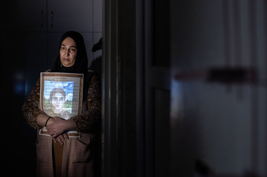 Sariye Tokay embraces a gift her son gave her years ago, as her son's photo is projected on her for a photo exhibition project, in Diyarbakır, southeastern Türkiye, Dec. 9, 2022. (AA Photo)