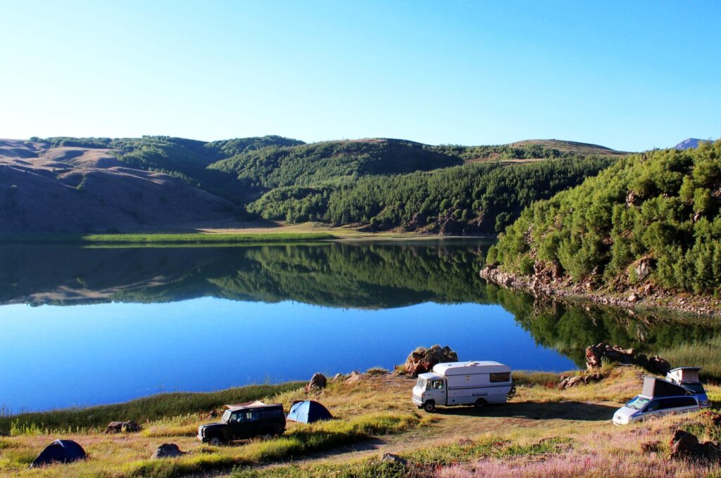 Camping cars and tents in front of a scenic mirroring crater lake near Lake Van in eastern Türkiye. (Shutterstock Photo)
