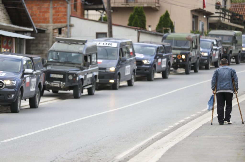 A man walks past a convoy of NATO-led peacekeeping force KFOR vehicles parked on a street in the town of Zvecan, northern Kosovo, Thursday, June 1, 2023. (AP File Photo)