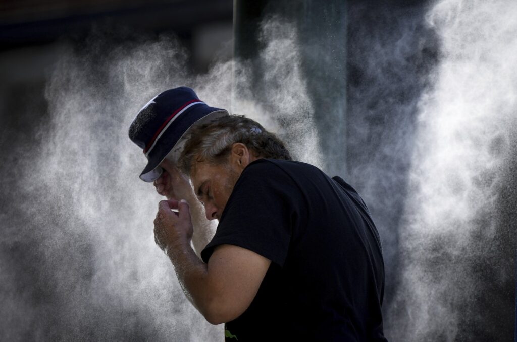 A man cools off at a temporary misting station deployed by the city in the Downtown Eastside due to a heat wave, in Vancouver, British Columbia, Aug. 16, 2023. (AP Photo)