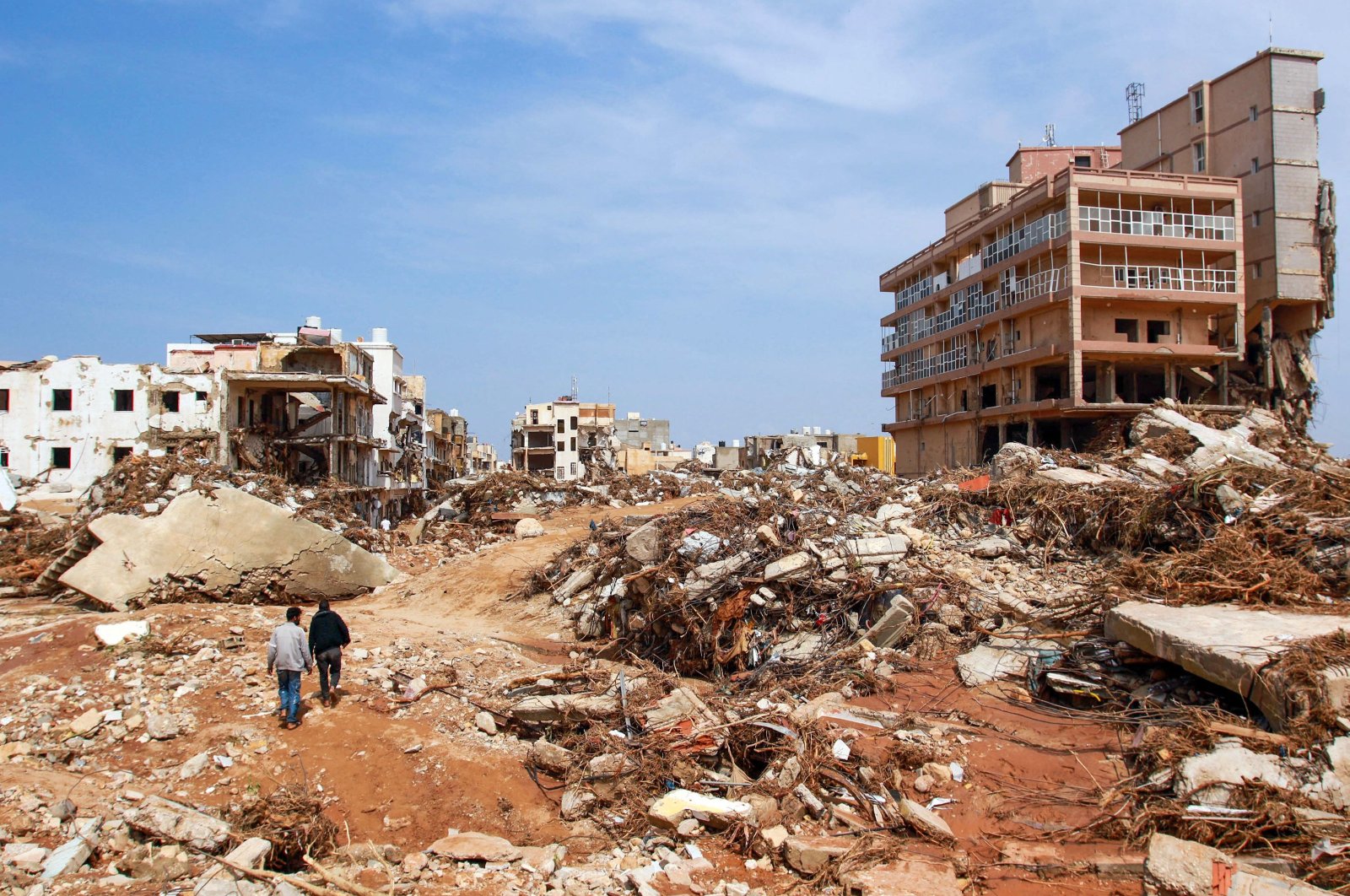Men walk past debris of buildings caused by flash floods in Derna, eastern Libya, Sept. 12, 2023. (AFP Photo)